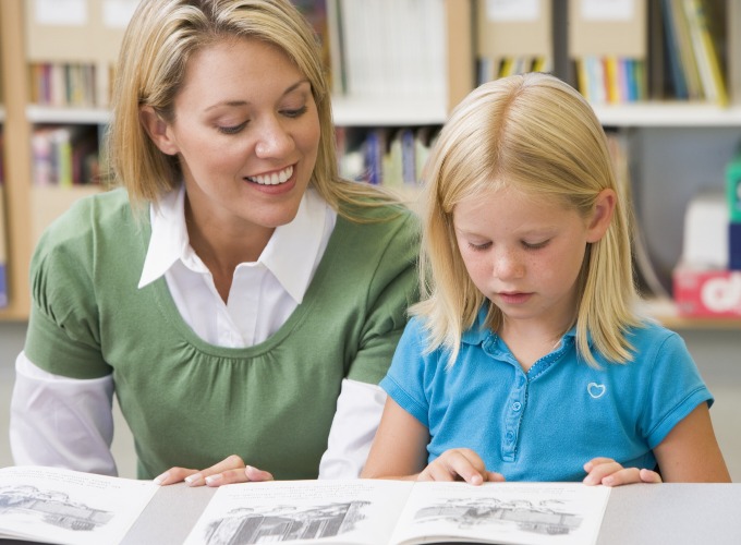 Lerares zit op tabouret naast kind Voetkruis van een tabouret met zachte wielen en een vergelijking met glijdoppen voor harde vloeren