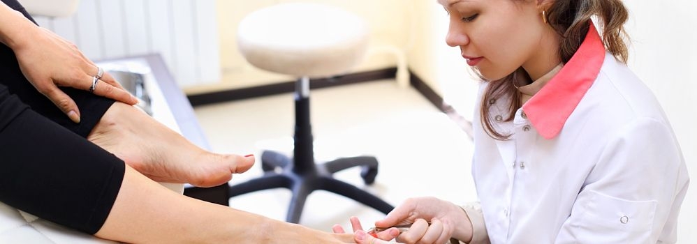 pedicure zit op tabouret Tabouret met ronde zitting en chromen voetkruis in een professionele werkomgeving